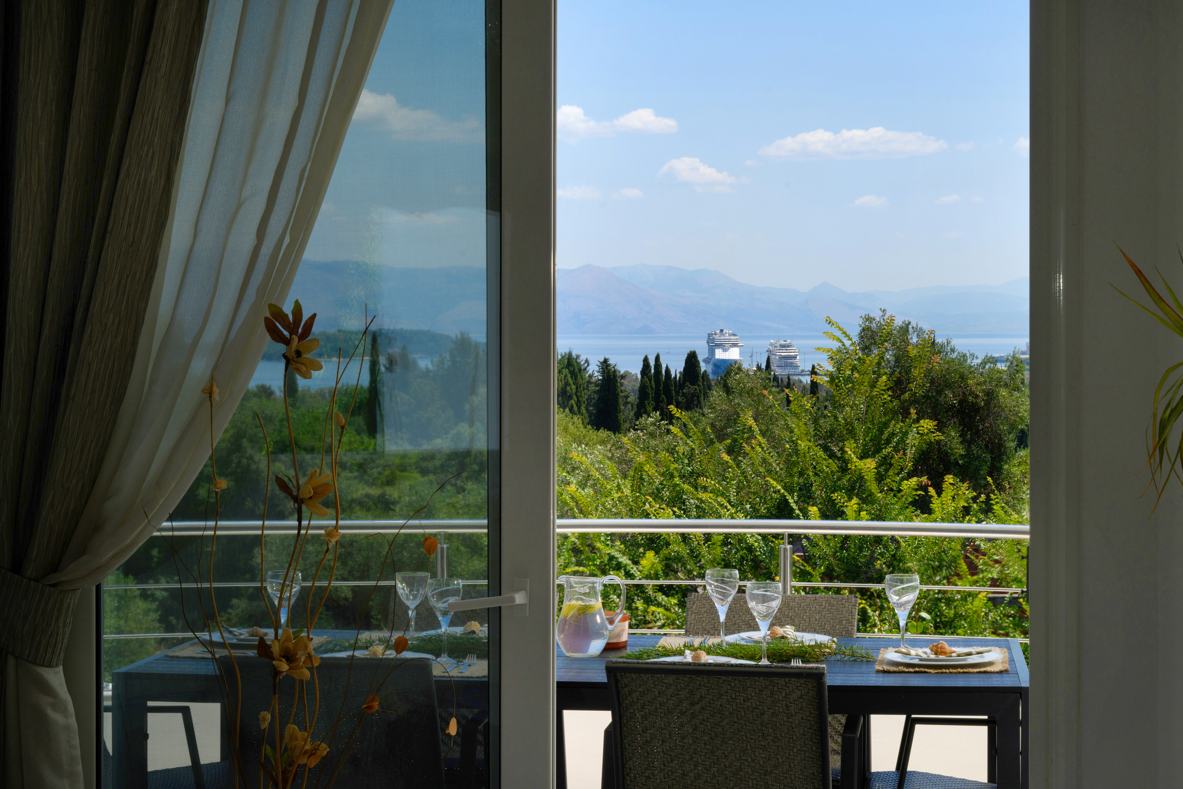 Outdoor dining table on terrace with panoramic sea view in Corfu