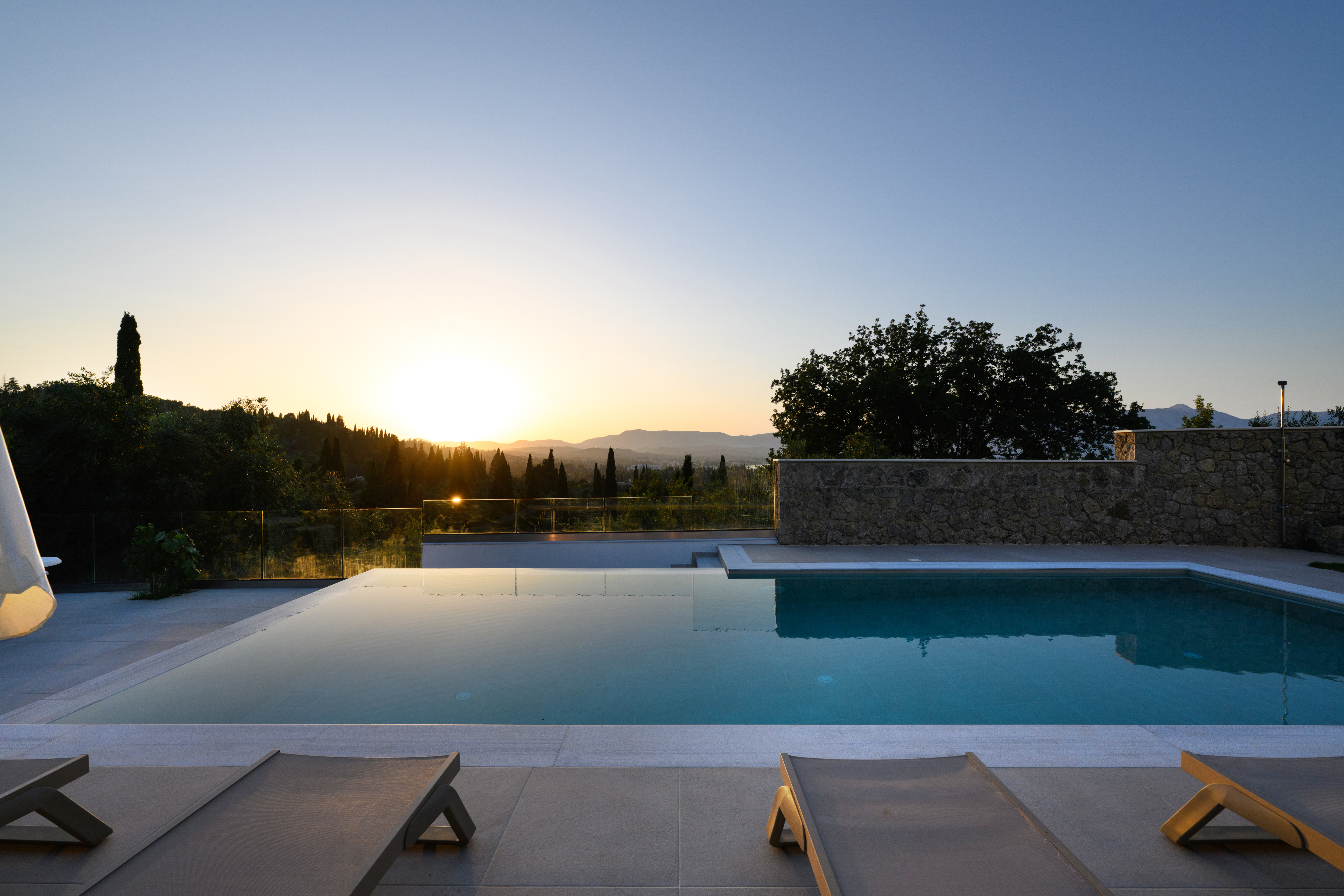 Infinity swimming pool terrace with sun loungers overlooking the sea in Corfu
